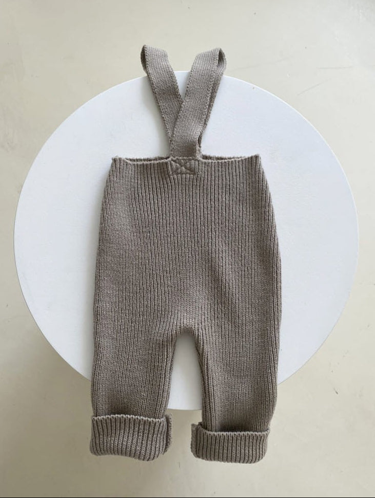 Brown knitted baby overalls with suspenders on a white background