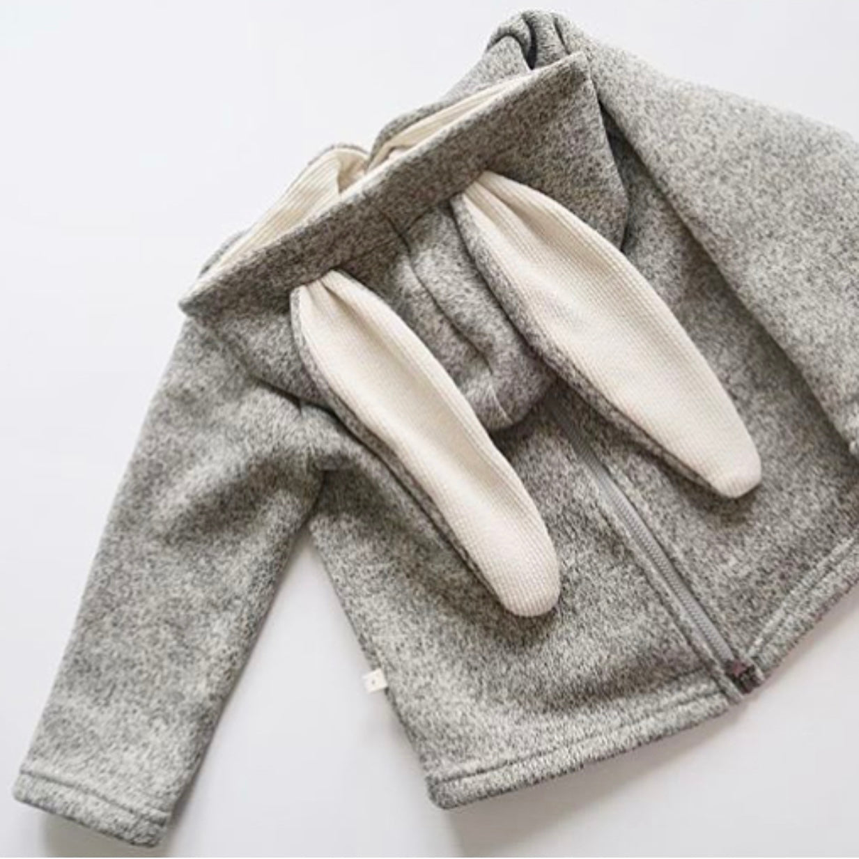 the back of a Gray fleece jacket with white bunny ears on a light gray background